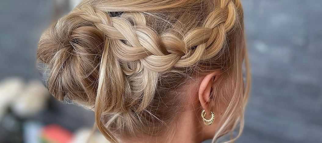 Elegant updo hairstyle with intricate braids and blonde highlights.